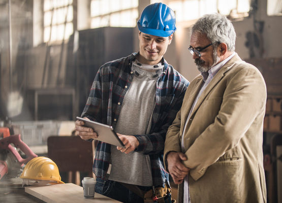 Construction worker speaking with executive